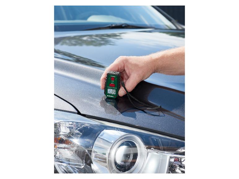 Een man gebruikt een PARKSIDE lakdiktemeter op de motorkap van een auto.