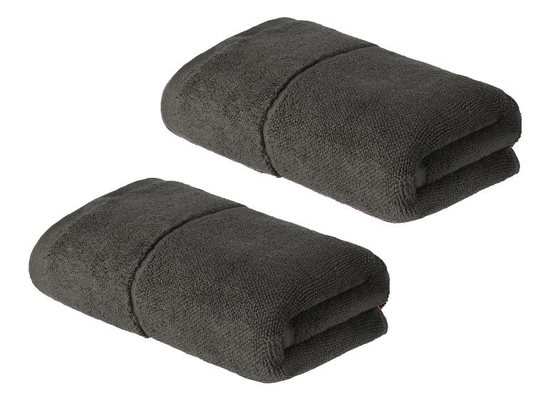Twee donkergrijze handdoeken, opgevouwen en klaar voor gebruik.