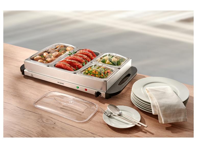 Roestvrijstalen voedselwarmer met vlees, aardappelen en groenten, op een houten tafel.