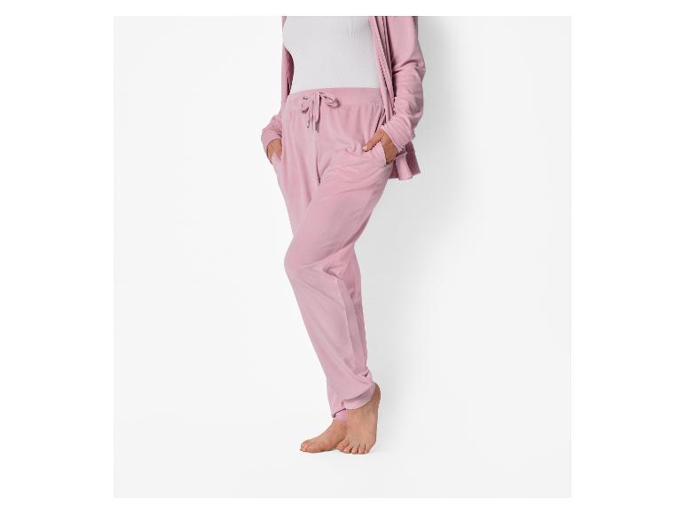 Vrouw in roze velours joggingbroek en bijpassend vest