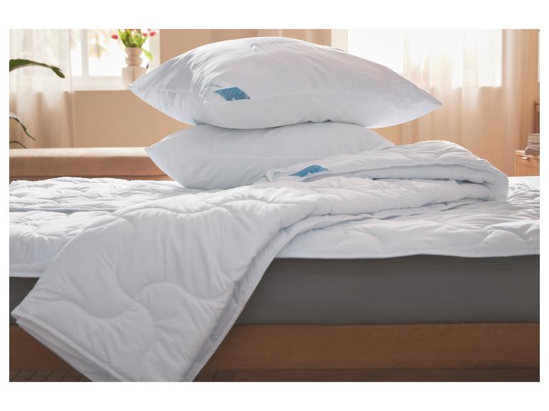 Witte kussens en een dekbed op een bed.