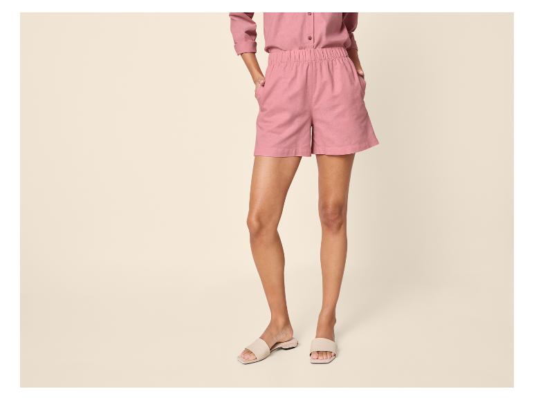 Vrouw in roze overhemd en korte broek, met beige sandalen.