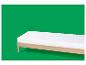 Eenvoudig houten bedframe met wit matras op een groene achtergrond.