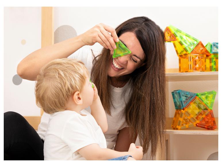 Bljide moeder en kind spelen met kleurrijke magnetische bouwblokken.
