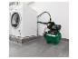 Groene huiswaterpomp aangesloten op een witte wasmachine in een wasruimte.