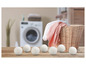 Wolwasballen op een houten tafel voor een wasmachine.