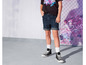 Een model draagt ​​een zwarte T-shirt met een grafische print, blauwe denim shorts en zwarte Converse sneakers.