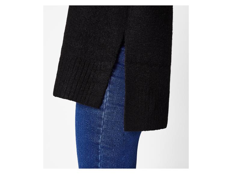 Zwarte trui met zijsplitten gedragen over een blauwe spijkerbroek