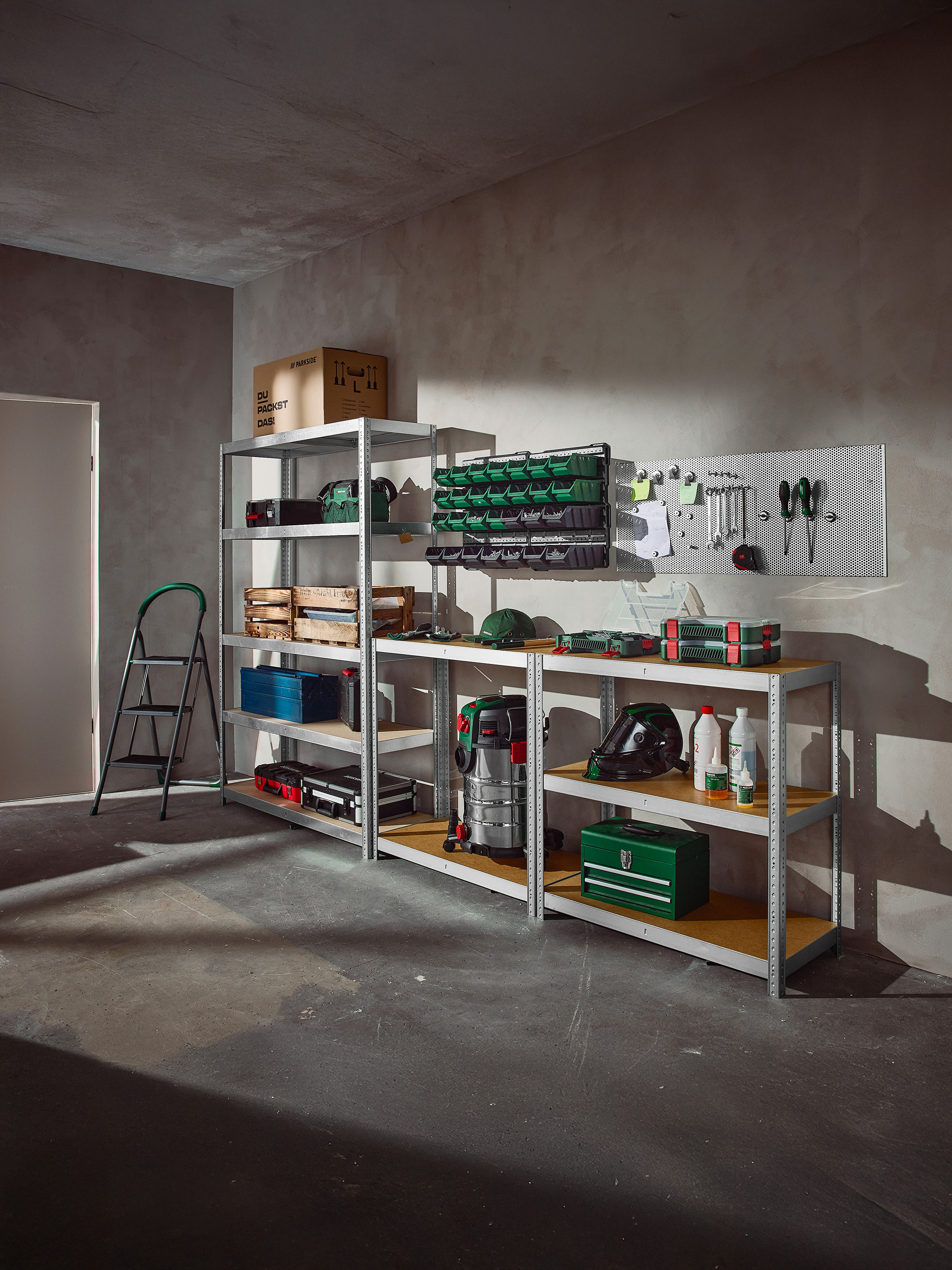 Georganiseerde garage met stellingen vol gereedschap, opbergdozen en werkplaatsuitrusting.