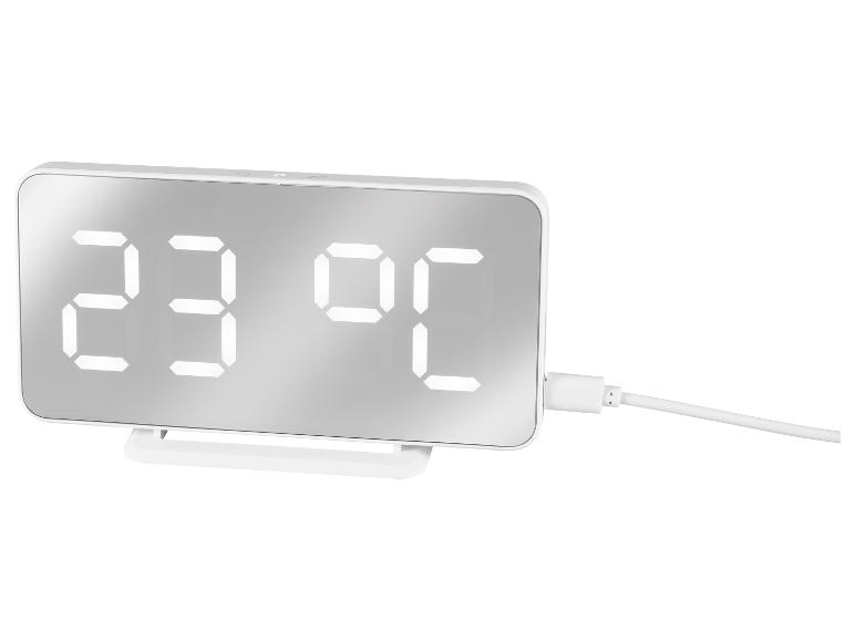 Witte digitale klok met temperatuurweergave en oplaadkabel