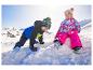 Twee jonge kinderen in kleurrijke LUPILU® sneeuwjassen spelen in de sneeuw