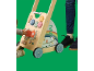 Peuter speelt met een houten loopwagen met activiteitenbord, naast een volwassene.