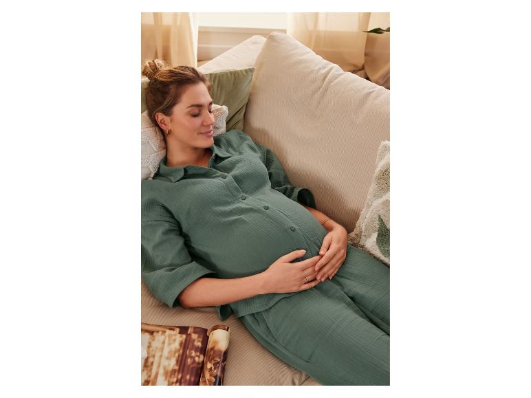 Zwanger vrouw in groene pyjama op de bank.