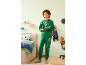 Jongen in een groen trainingspak met capuchon houdt een gamecontroller vast in een kinderkamer.
