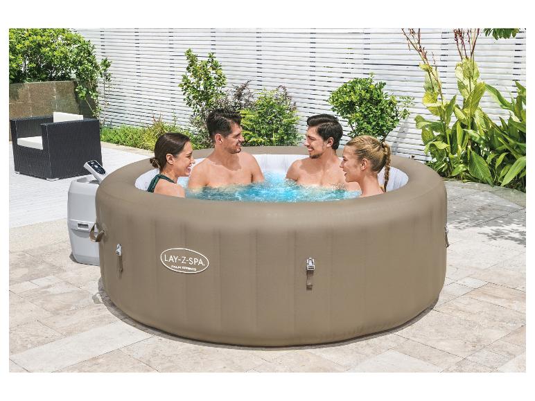 Vier mensen genieten van een opblaasbare jacuzzi buiten.
