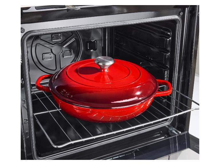 Rode gietijzeren braadpan in een open oven.