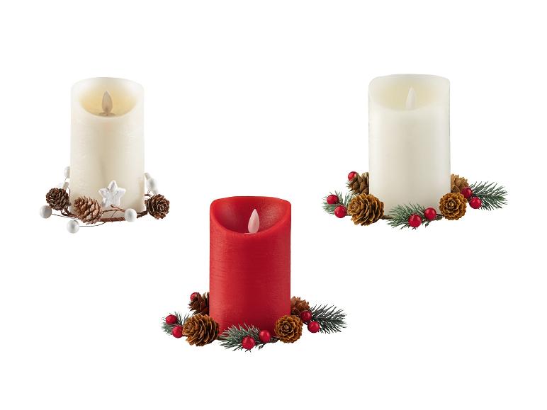 Drie decoratieve LED-kaarsen, twee witte en één rode, met feestelijke ornamenten.