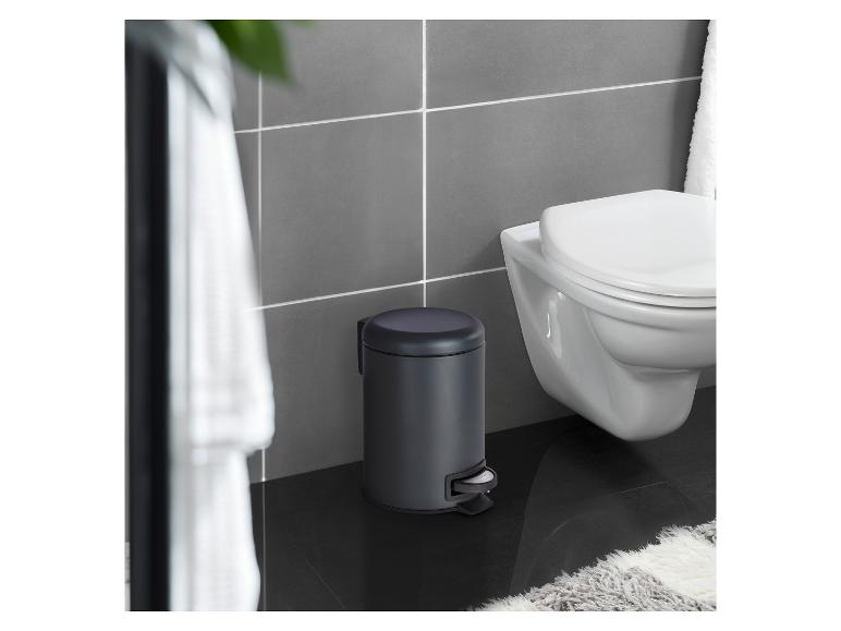 Een donkergrijze prullenbak in een badkamer naast een hangend toilet.