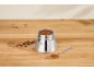 Mokkapot gevuld met gemalen koffie, koffiebonen en een lepel op een houten tafel.