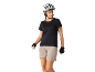 Vrouw met witte fietshelm, zwart T-shirt en beige shorts, met fietshandschoenen.