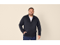 Lachende man in donkerblauw vest met rits en jeans.