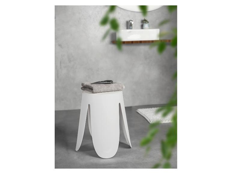 Moderne witte kruk met handdoek en cosmetica in een badkamer.