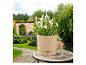 Beige plantenpot met witte planten op een mozaïektafel in een tuin.