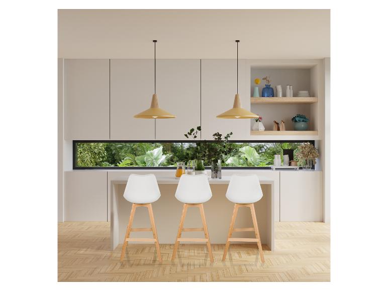 Moderne keuken met witte barkrukken, houten vloer en een lang raam.