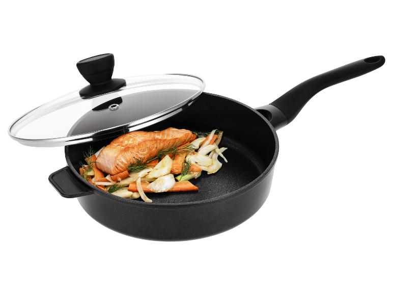 Zwarte koekenpan met glazen deksel, met zalm en groenten.