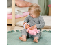 Een peuter speelt met een zachte babypop op een groen vloerkleed.