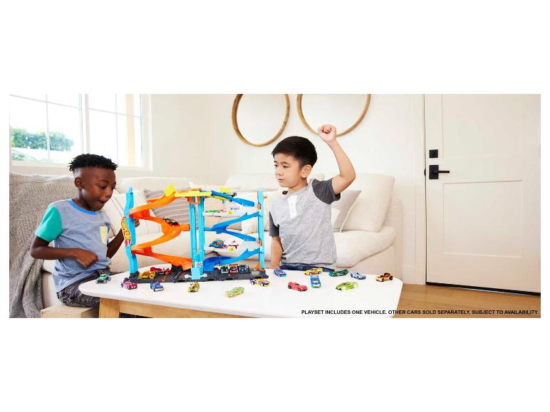 Twee kinderen spelen met een Hot Wheels garage speelset en meerdere speelgoedauto's.