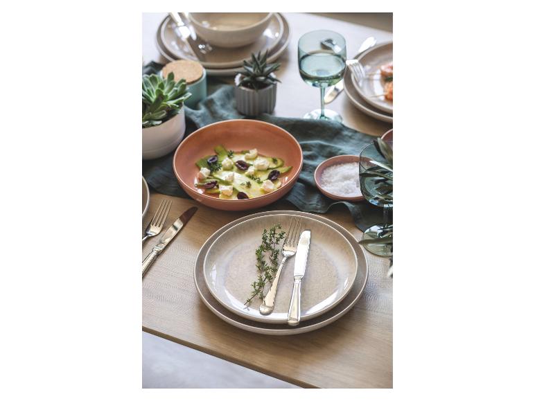 Tafel gedekt met gerechten, waaronder salade, en bestek.