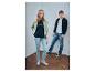 Twee jonge mensen dragen bedrukte T-shirts, hoodies en jeans tegen een witte achtergrond.