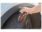 Hand houdt digitale bandenprofielmeter vast op winterband van auto.