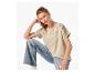 Vrouw in lichtbeige T-shirt met borduursel en lichtblauwe jeans