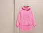 Een roze oversized hoodie met capuchon hangt aan een kledingrek.