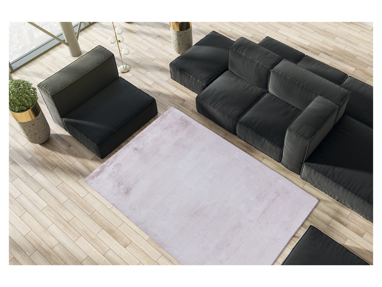 Een roze vloerkleed op een houten vloer met een zwarte modulaire bank.