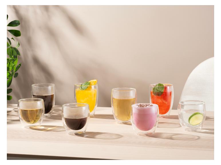 Diverse dranken in dubbelwandige glazen op een houten tafel met natuurlijk licht.