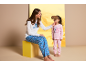 Vrouw en kind in bijpassende pyjama's, vrouw houdt slaapmasker voor het gezicht van het kind.