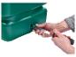 Handen installeren een groene plastic buis in een opvangtank met een gereedschap.