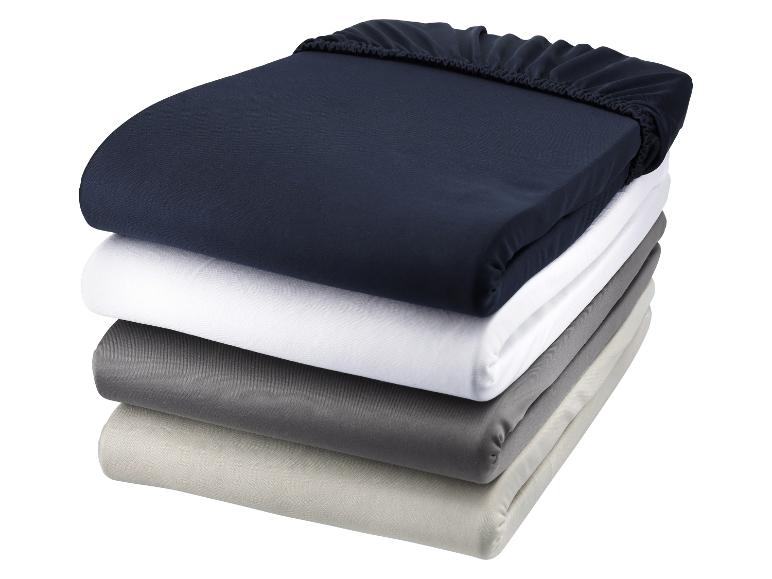 Een stapel matrasbeschermers in neutrale kleuren.