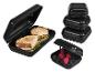 Zwarte plastic lunchboxen voor sandwiches en fruit, één open met inhoud.