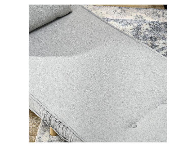 Lichtgrijze bank met kussen en knopen op een patroonkleed.