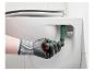Hand in werkhandschoen gebruikt een wc-brilsleutel om een wc-bril te installeren.