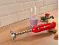 Rode staafmixer met maatbeker, bessen en smoothie op een houten ondergrond.