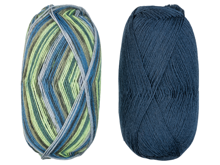 Twee bollen garen, één veelkleurig in blauw, groen en grijs, en één effen donkerblauw.