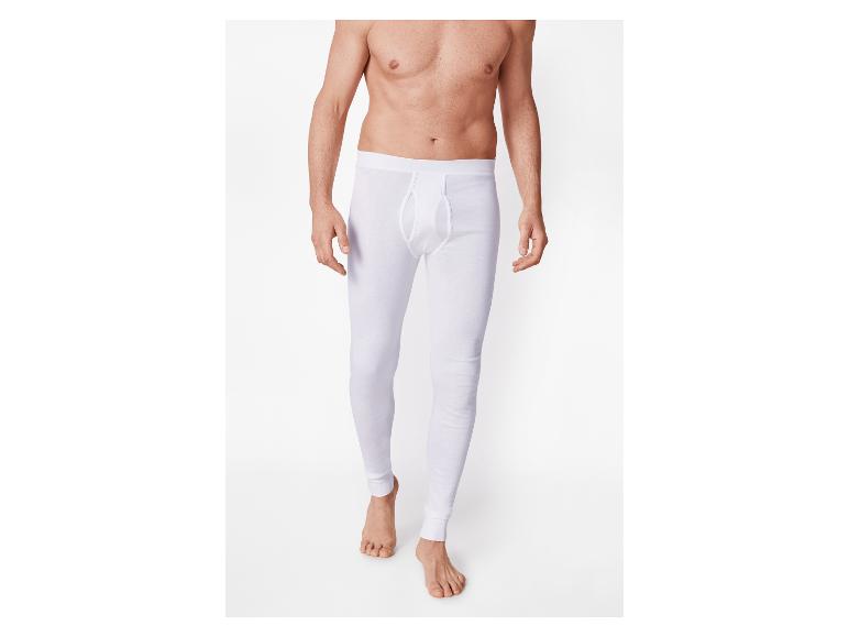 Man zonder shirt in witte lange onderbroek tegen een witte achtergrond.