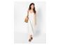 Vrouw in witte maxi-jurk, bruine sandalen en strooien tas.