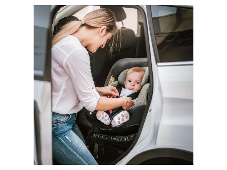 Vrouw gespt baby vast in autostoel in auto.