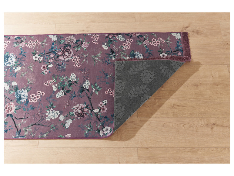 Een roze vloerkleed met bloemenprint en franjes.